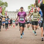 A man wearing a purple Cats Protection branded t-shirt running in the London Marathon
