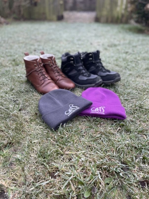 Two Pairs Of Boots And Two Beanies On Frosty Grass
