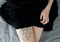A geometric cat tattoo on the thigh of a women wearing a black skirt