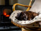 black cat sleeping on a chair in front of a lit fireplace